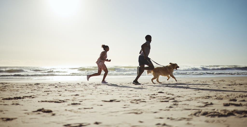 Fitness, couple and dog at beach for running, health and exercise in nature, sand and blue sky back.