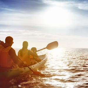 Kayaking concept with family of father mother and son swimming at sea at sunset time. Space for text