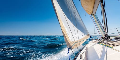 White sailing boat at open sea in sunshine