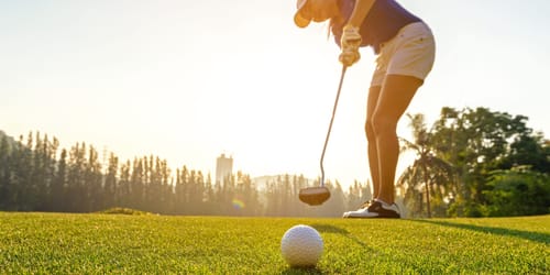 Sport Healthy. Golfer asian sporty woman focus putting golf ball on the green golf on sun set evening time. Healthy and Lifestyle Concept